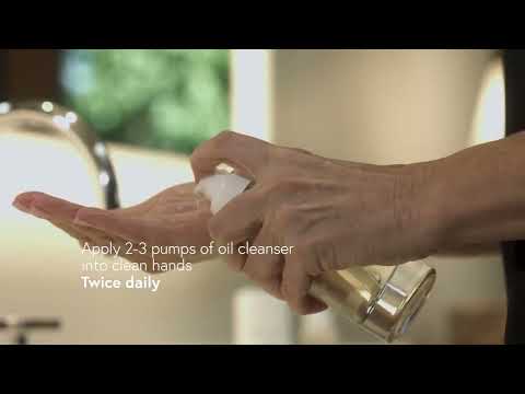 Person applying 2-3 pumps of oil cleanser into hands for skincare routine.